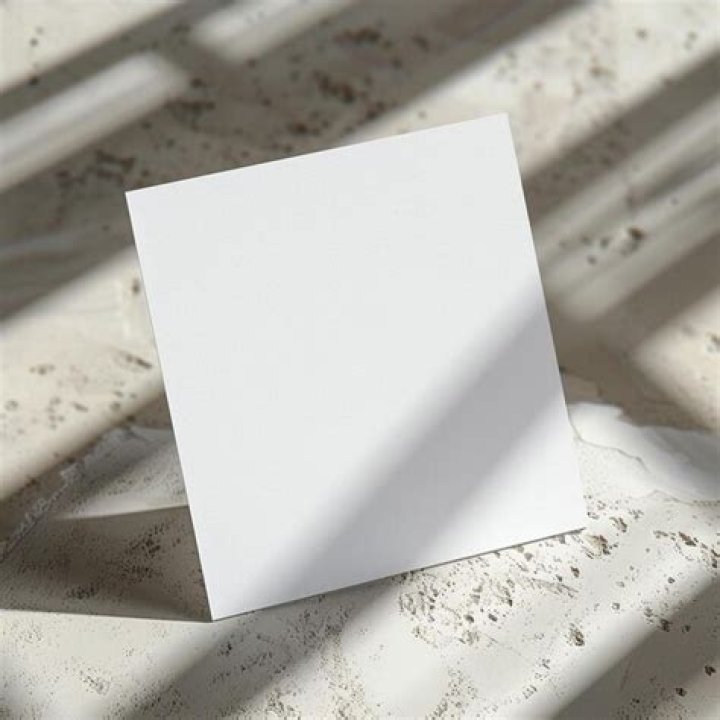 a piece of paper sitting on top of a table next to a flower covered wall